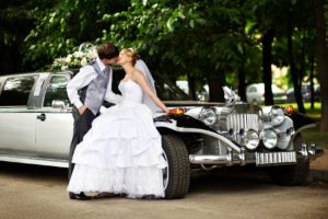 Happy groom adn bride about retro limousine